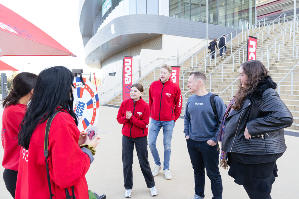 Delegates stand outside the stadium in team jackets, State of Social ’21