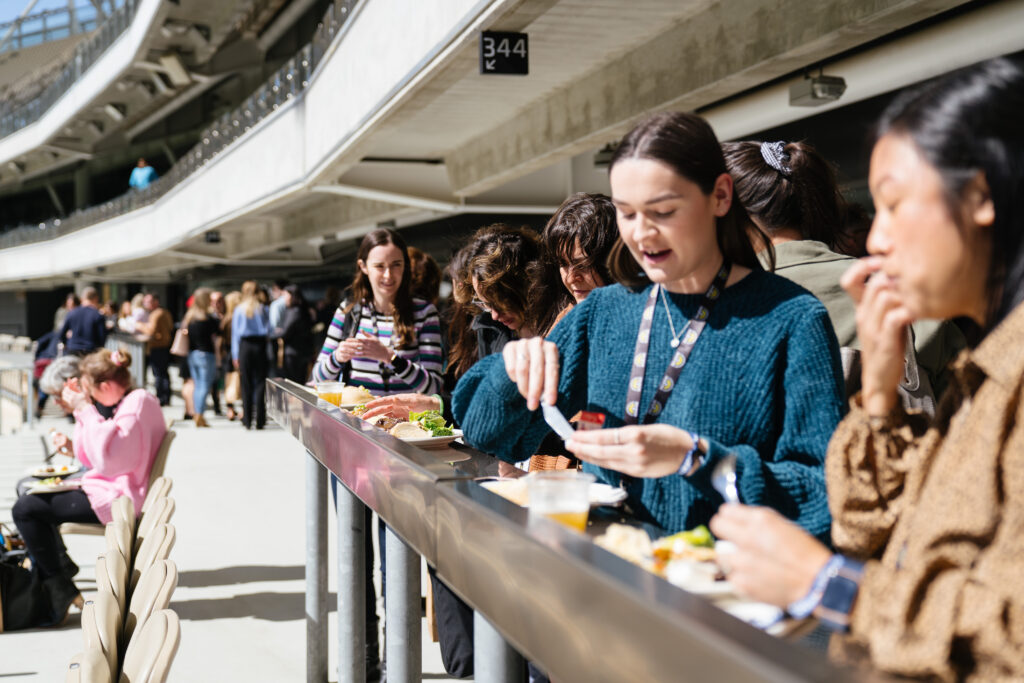 Delegates eat lunch at the long bench on the stadium concourse, State of Social ’21