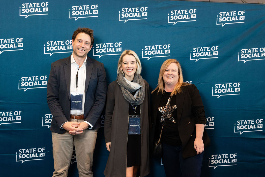 Three delegates pose in front of the State of Social backdrop, State of Social ’21
