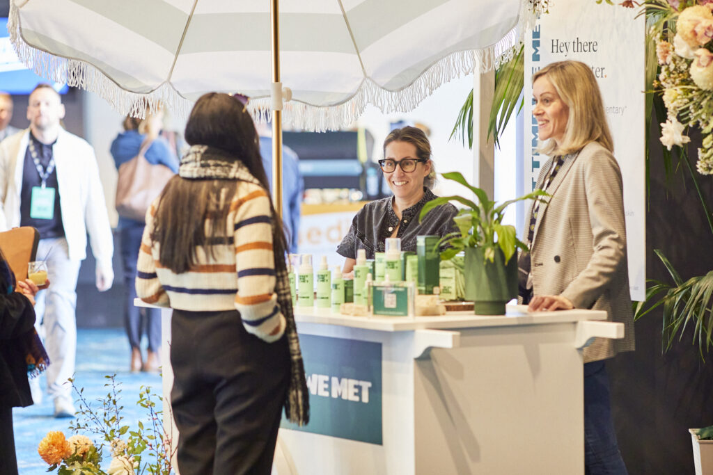 Delegate talks with a host at a branded flower-decorated stand, State of Social ’23