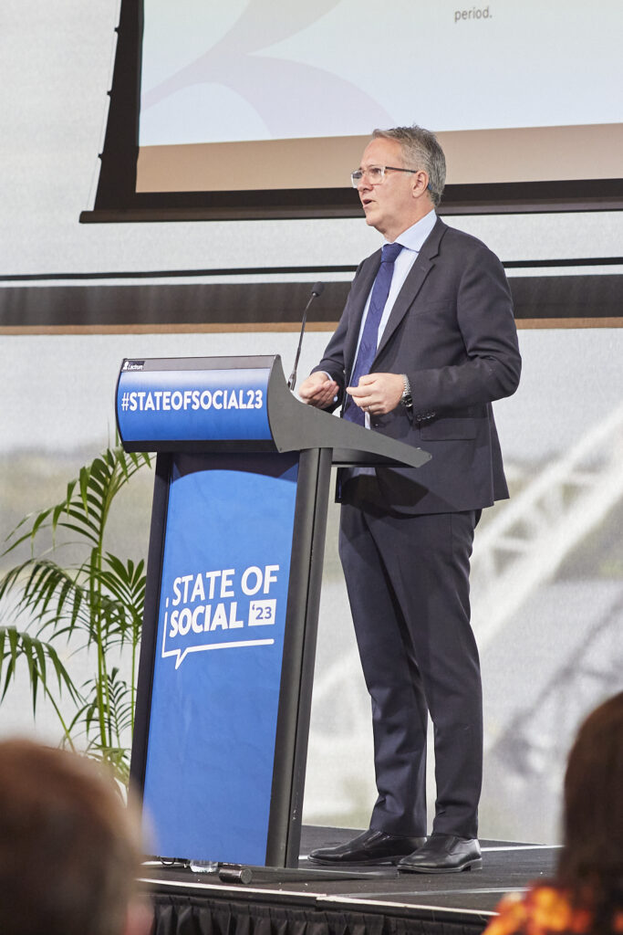 Speaker in a suit presents at the State of Social lectern, State of Social ’23