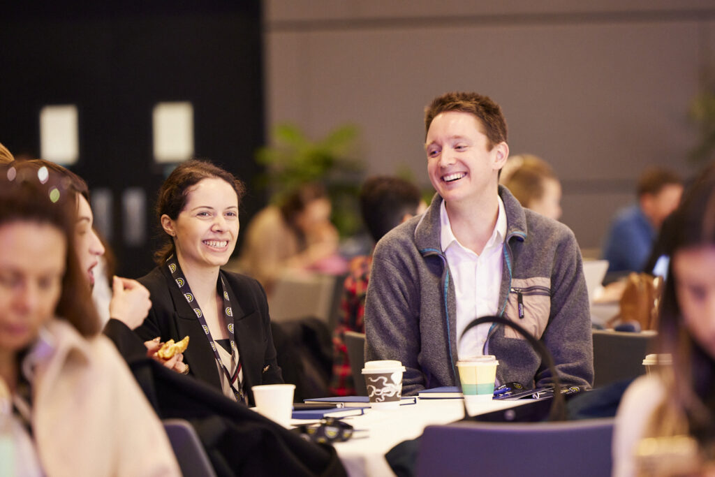 Delegates seated at a table smile during a session, State of Social ’23
