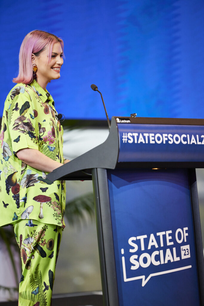 Speaker in a green patterned suit presents at the State of Social lectern, State of Social ’23