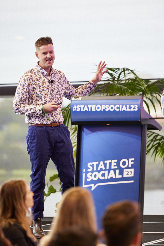 Speaker in a patterned shirt presents at the State of Social lectern, State of Social ’23