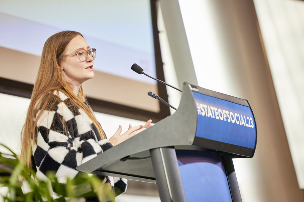 Speaker in a chequered jacket presents at the State of Social lectern, State of Social ’23