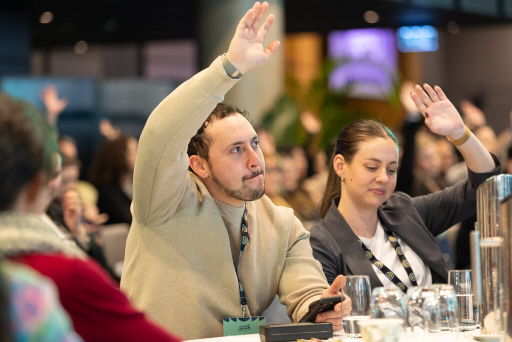 Delegates raise their hands to answer a question from the audience