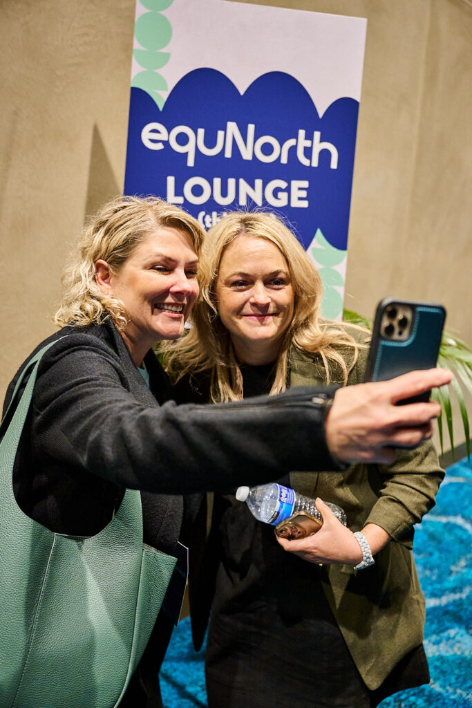 Two delegates take a selfie in front of the equNorth Lounge sign, State of Social ’25