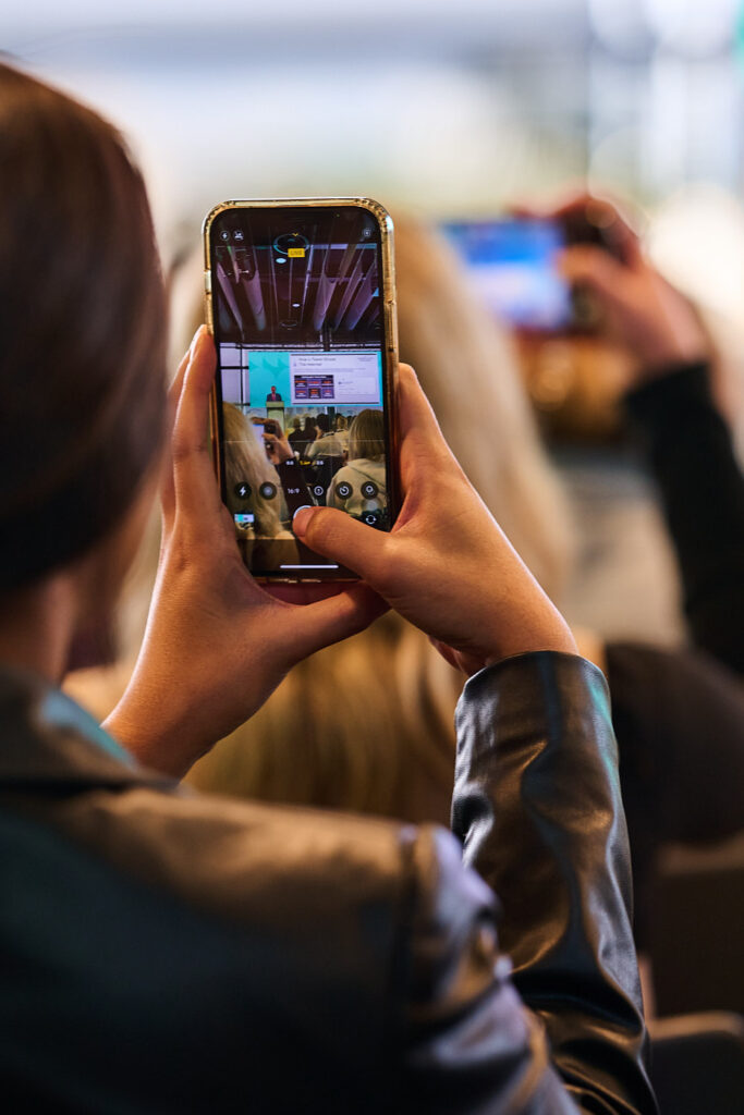 Delegate holds up her phone to film the stage, State of Social ’25