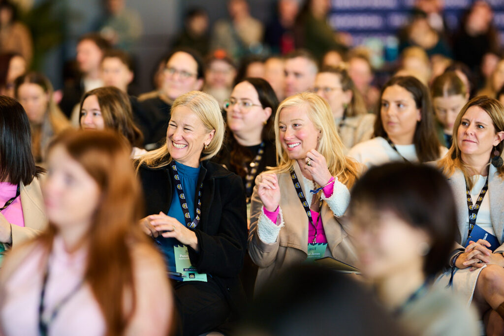 Delegates in the front rows smile and listen, State of Social ’25