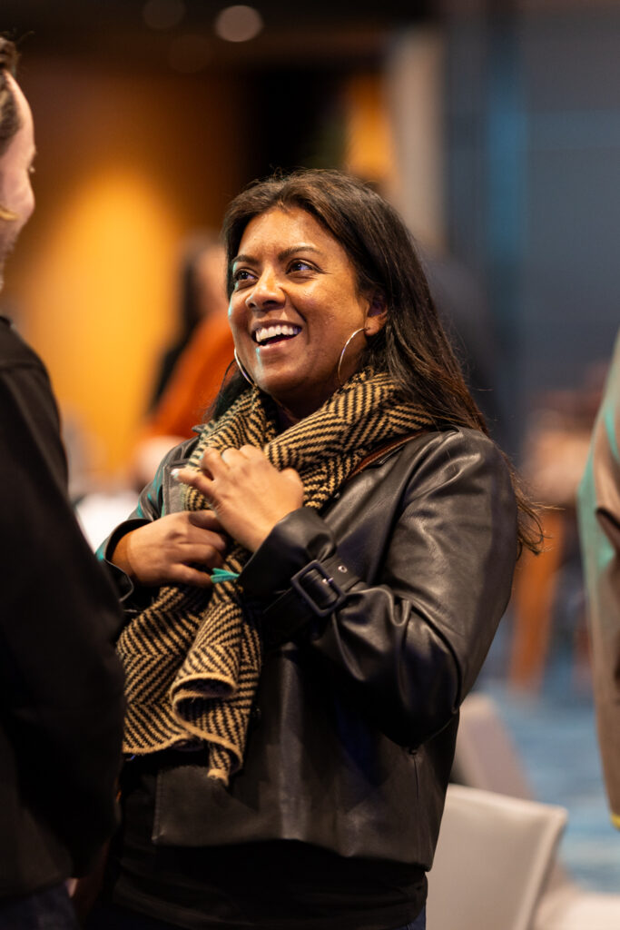 Delegate in a leather jacket and scarf laughs during a break, State of Social ’25