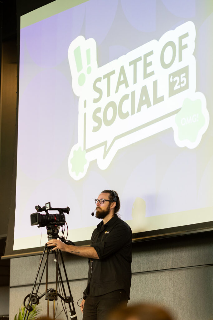 Camera operator films beside a screen showing the State of Social ’25 logo, State of Social ’25