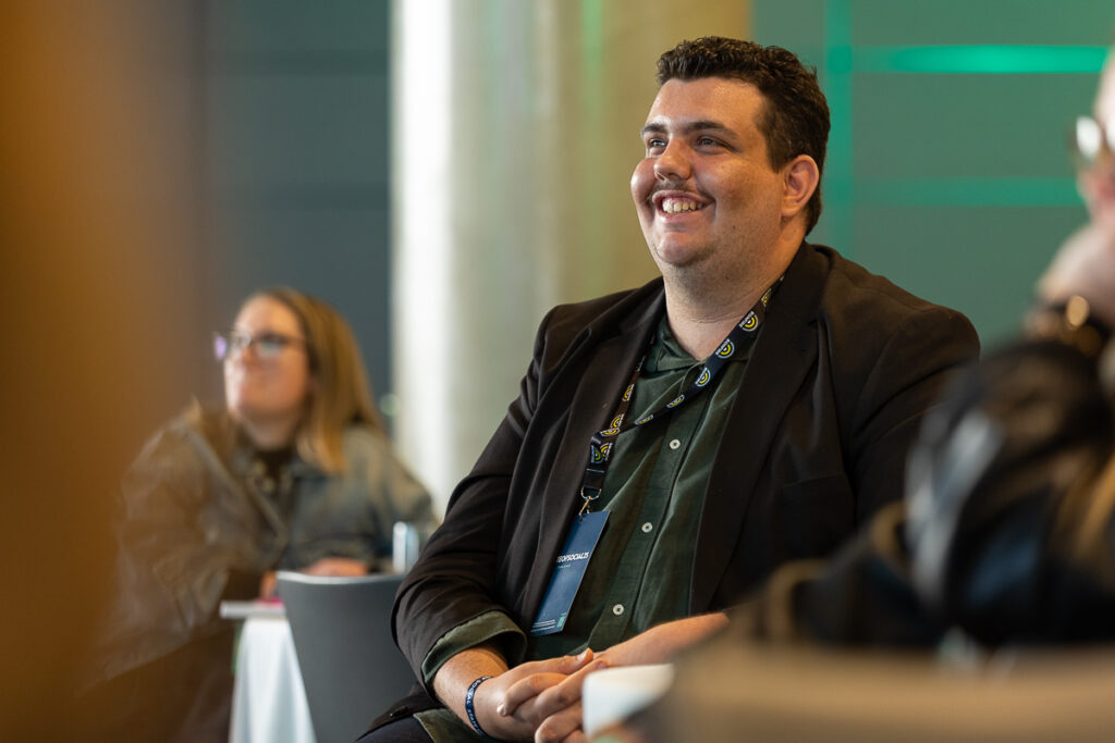 Smiling delegate in a dark blazer enjoys a session