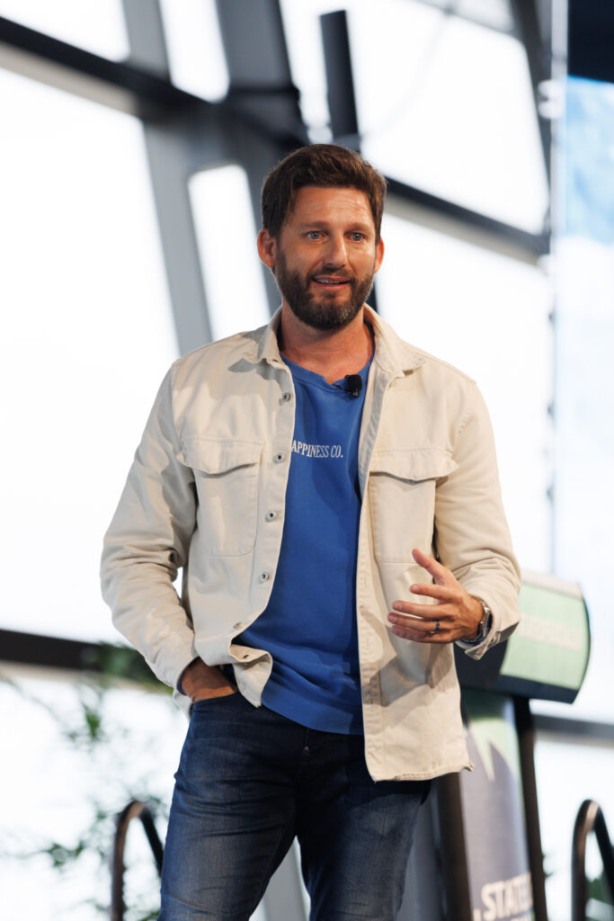 Speaker in a denim jacket gestures on stage, State of Social ’26