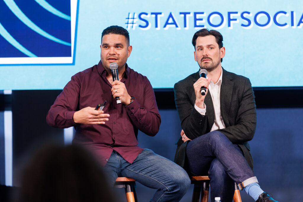 Two panellists with microphones seated on stools on stage, State of Social ’26