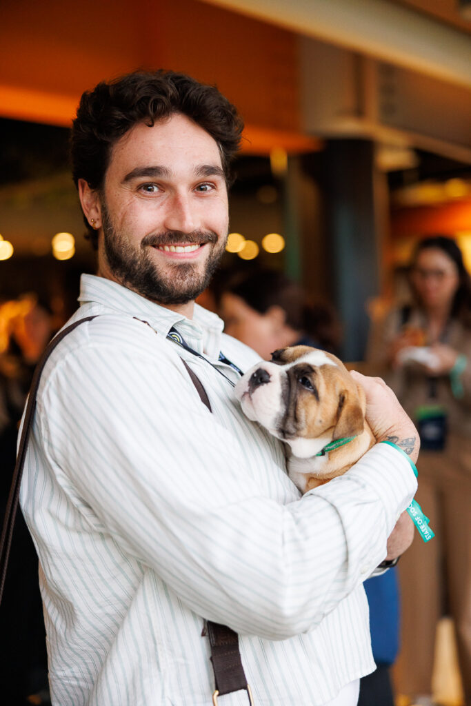 Smiling delegate holds a small bulldog puppy, State of Social ’26