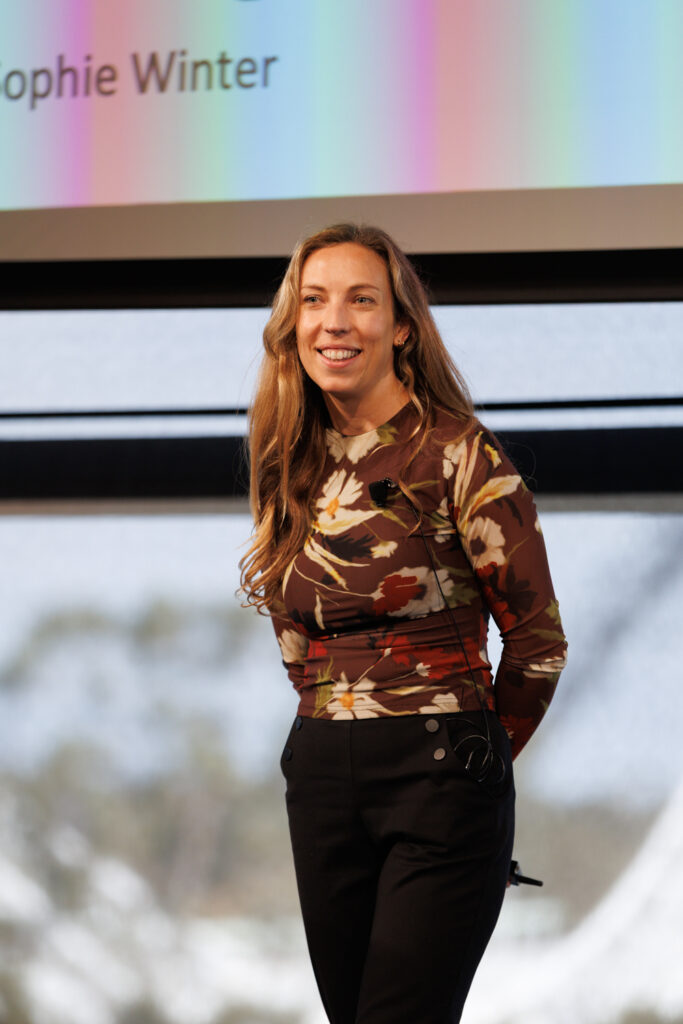 Speaker in a patterned top walks across the stage, State of Social ’26