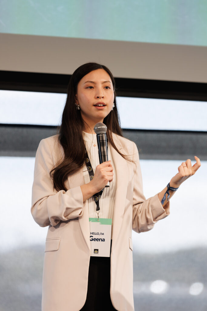 Speaker in a cream blazer holds a microphone and gestures, State of Social ’26